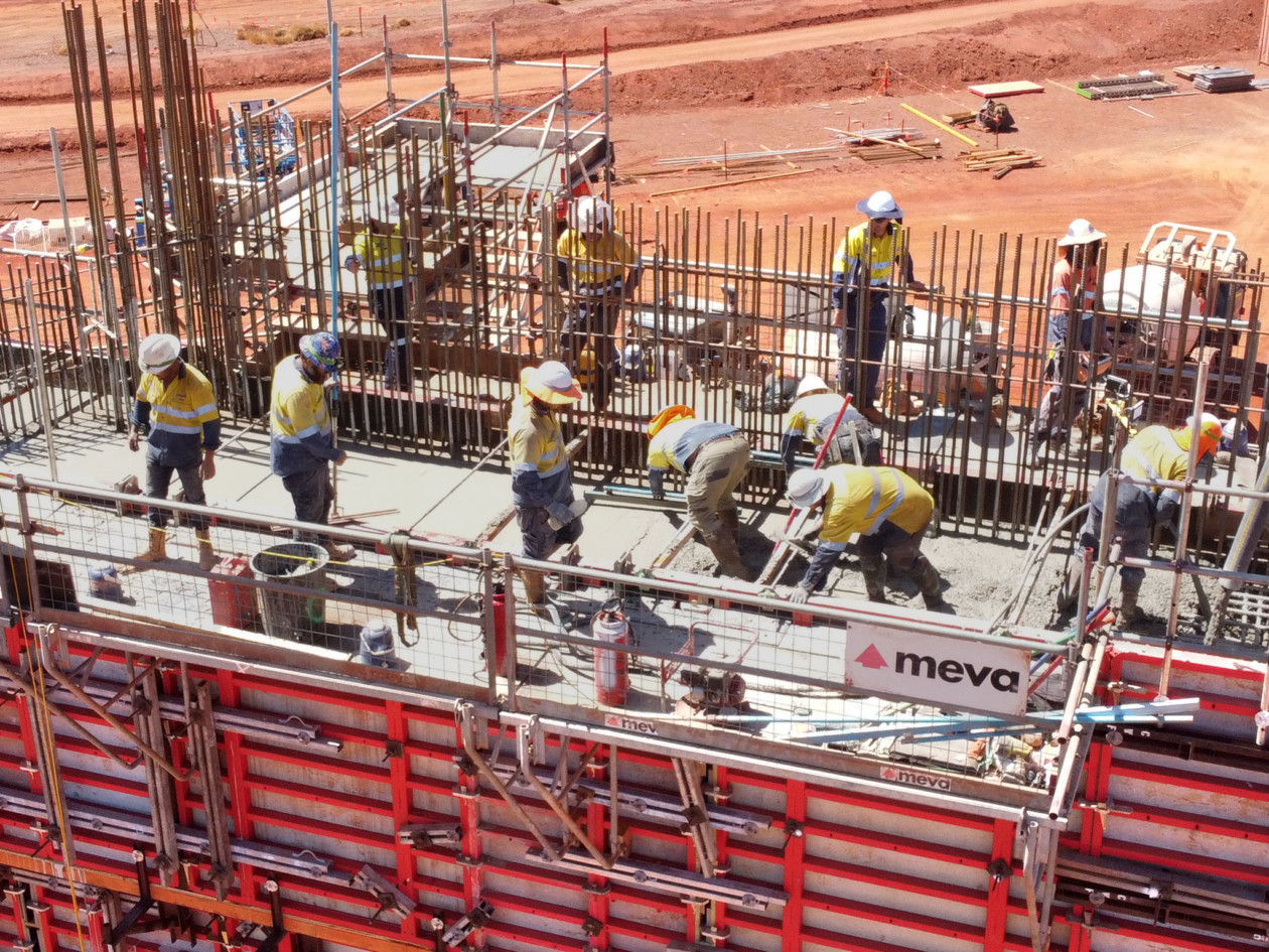 Bauarbeiter beim Einfüllen von flüssigen Beton in eine Wandschalung